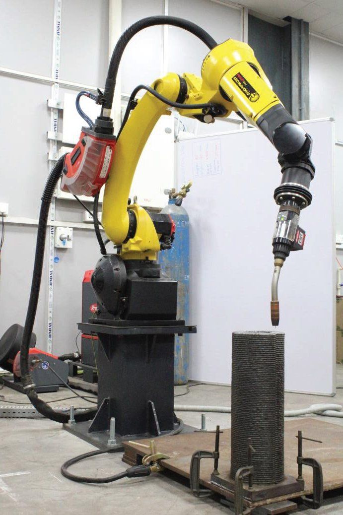 GoAero WAAM cell with industrial robot and a deposited steel cylinder