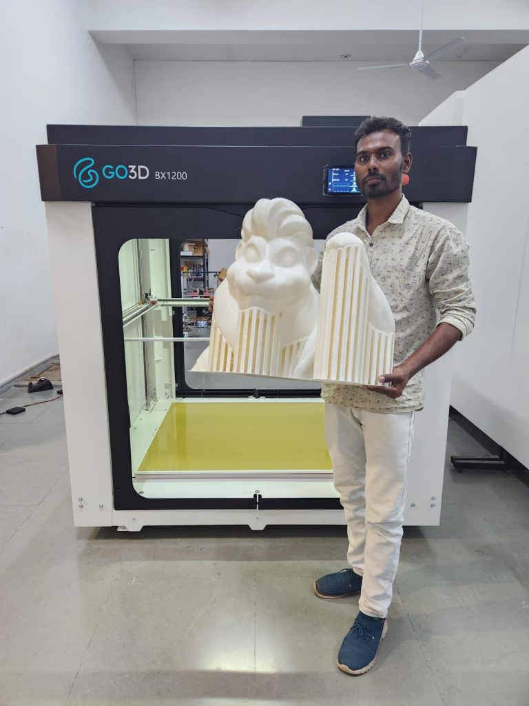 Operator holding the 3D printed white PLA lion mascot head and body sections in front of the Go3D BX 1200